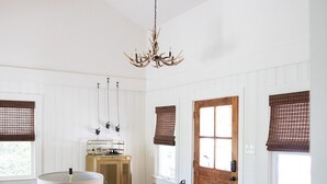 Un salón amplio con candelabro, una puerta de madera y un banco junto a la ventana.