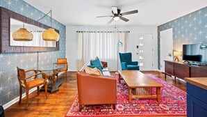 A modern living room with a sofa, chairs, a coffee table, and a TV. - Cozy 3BR Getaway  Pets OK + Fenced Yard (Jeffersonville)