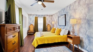 A bedroom with a bed, two chairs, a desk, a ceiling fan, and a TV. - Cozy 3BR Getaway  Pets OK + Fenced Yard (Jeffersonville)