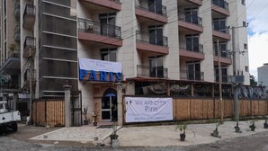 En byggnad med flera våningar, med en skylt som visar texten ”PARIS” och en banderoll med texten ”VI HAR ÖPPNAT – Paris”.