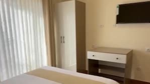 Ett hotellrum med en säng, en garderob, ett skrivbord och en tv som är monterad på väggen.