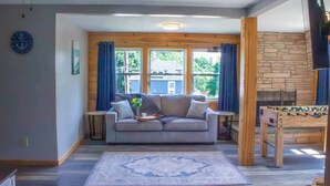 A cozy living room with a sofa, a coffee table, and a foosball table. - The Crossmon House (Alexandria Bay)