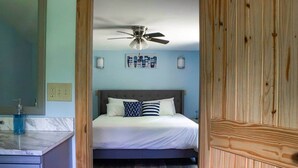 A bedroom with a bed, a ceiling fan, and a wall-mounted light fixture. - The Crossmon House (Alexandria Bay)