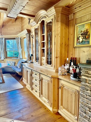 A wooden interior with a large cabinet, a stone wall, and a painting.