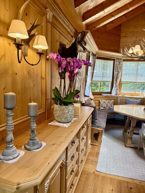 A wooden interior with a dining area, a wall-mounted deer head, and a potted orchid.