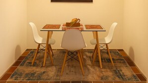 Spiseområde med et bord, stole, et tæppe og en vægmonteret lampe.