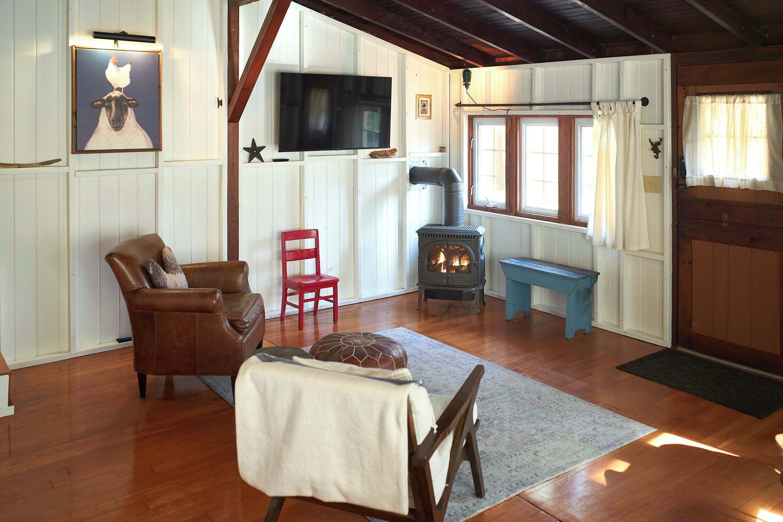 A cozy living room with a fireplace, a television, and a red chair.