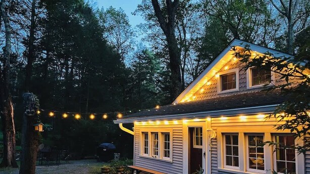 Una casa con porche, luces colgantes y una pequeña terraza.