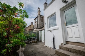 A residential building with a white exterior, a visible door, and a small outdoor seating area with a table and chairs. - Limefield Residence near Edinburgh (West Calder)
