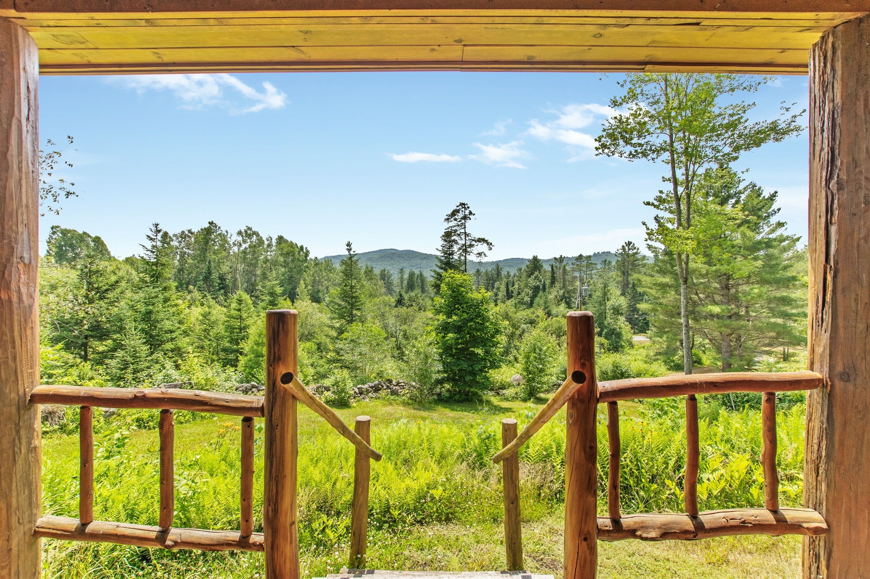 A wooden balcony with a view of a forested landscape.