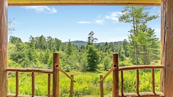 A wooden balcony with a view of a forested landscape.