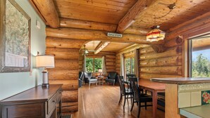 A log cabin interior with a dining area, a map on the wall, and a sign reading "DALTON". - Mountain View Log Cabin in the White Mountains (Dalton)