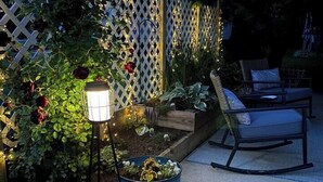 A garden area with a wooden planter, a metal lamp post, and a seating area with a chair and a table. - Port Clinton Lakeside Escape (Erie Township)