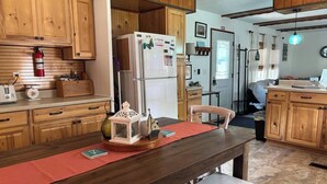 A kitchen with wooden cabinets, a refrigerator, a wooden dining table with a red placemat, and a small lantern. - Port Clinton Lakeside Escape (Erie Township)
