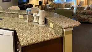A hotel room with a kitchen area, a television, a ceiling fan, and a view of the outdoors through the windows. - Luxury First Floor Villa - Free Daily Golf and Tennis Included (Hilton Head Island)
