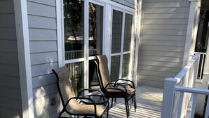 A covered porch with a white railing and a seating area with chairs. - Luxury First Floor Villa - Free Daily Golf and Tennis Included (Hilton Head Island)