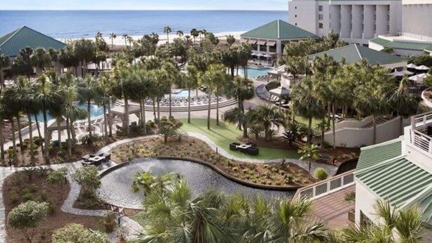 A resort with a pool, palm trees, and a view of the ocean. - Luxury First Floor Villa - Free Daily Golf and Tennis Included (Hilton Head Island)
