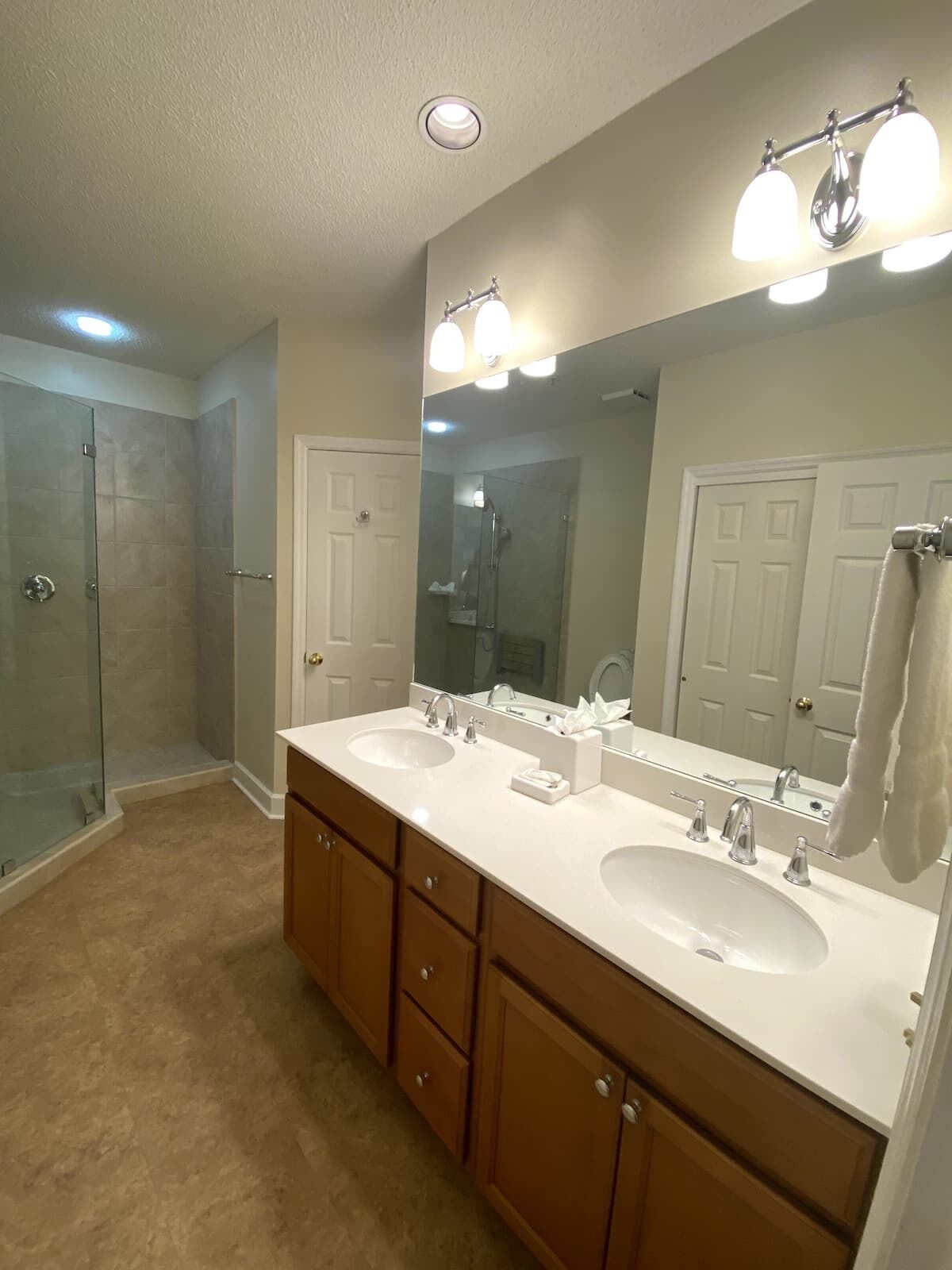 A bathroom with two sinks, a large mirror, and a shower.