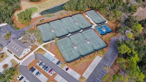 An aerial view of a sports complex with multiple tennis courts, a parking area, and surrounding greenery. - Luxury First Floor Villa - Free Daily Golf and Tennis Included (Hilton Head Island)