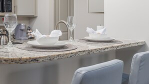 A modern kitchen with granite countertops, white cabinets, and a dining area with two chairs. - 3 mins from Space Center &BridgeStreet. (Huntsville)