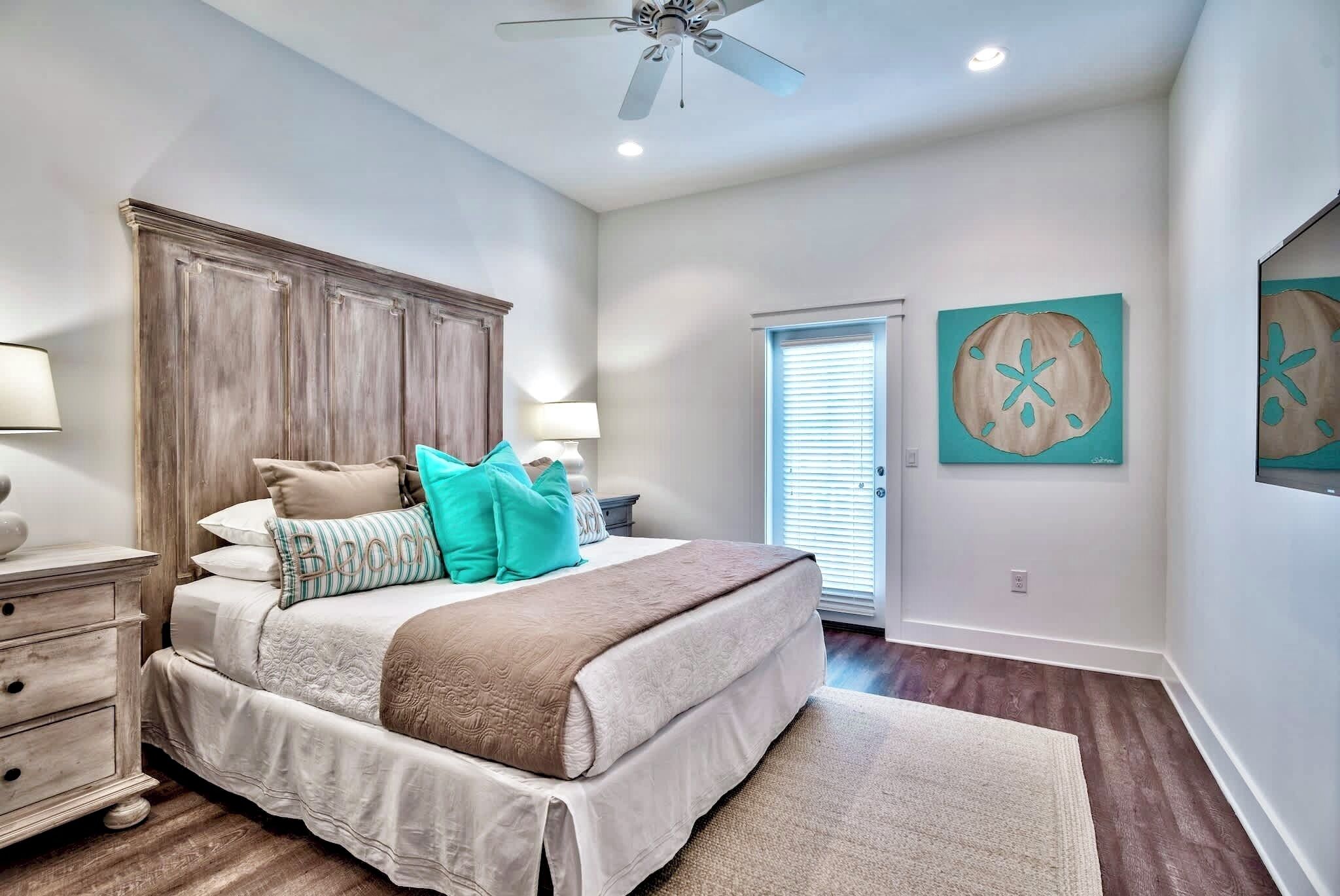 A bedroom with a large bed, wooden headboard, two bedside tables with lamps, and artwork on the walls.
