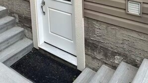Eine weiße Haustür mit Fensterglas, ein kleines Fenster darüber und ein Briefkasten links.