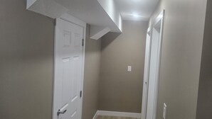 A narrow hallway with beige walls and white doors.