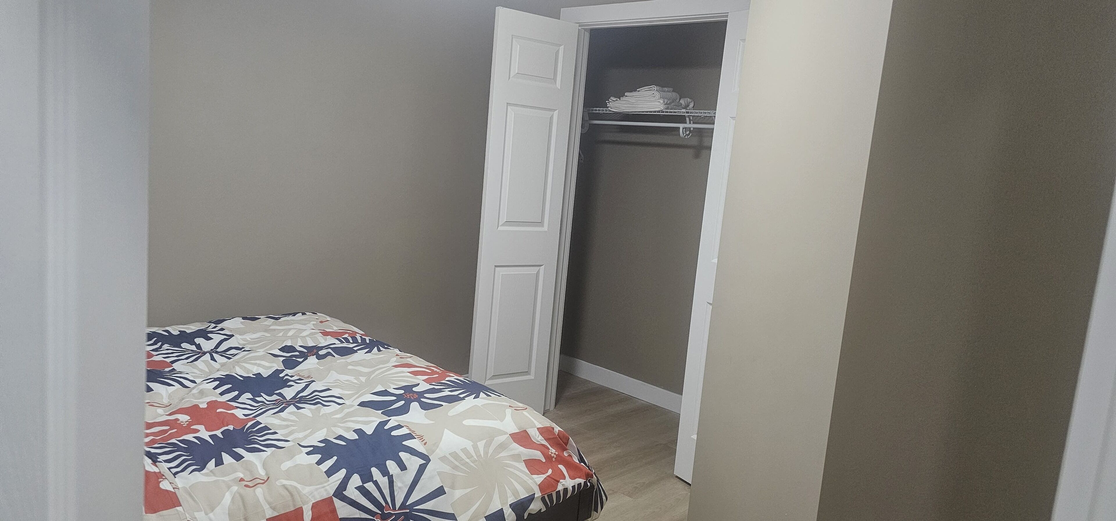 Une chambre à coucher comprenant un lit, une armoire et une porte donnant sur une autre pièce.