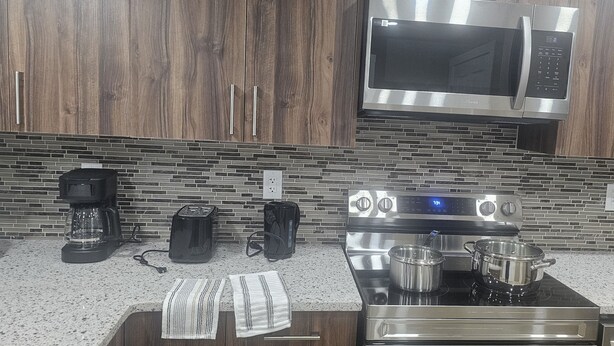 A kitchen with a stainless steel stove, a microwave, and a coffee maker.