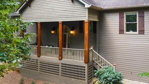 A two-story house with a covered porch and a staircase leading to the second floor.