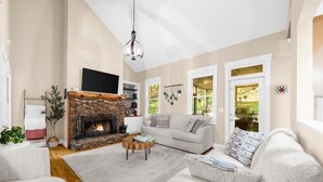 A living room with a stone fireplace, a grey sofa, and a coffee table.