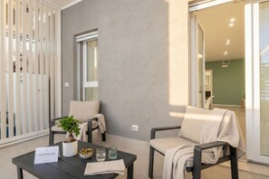 Une pièce moderne avec un mur gris, une fenêtre, un canapé, une table avec une plante et un verre.