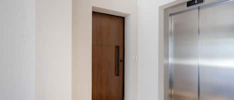 Un ascenseur moderne doté d’un écran numérique, d’une porte en bois et d’un paillasson.