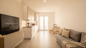 A modern apartment with a TV on a wooden stand, a kitchenette, a dining area, and a living room with a sofa. - Borgo Felice 5 (Cozy Apartment with Balcony) (Bari)