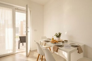A dining area with a table set for two, a chair, a potted plant, and a sign with a website address. - Borgo Felice 5 (Cozy Apartment with Balcony) (Bari)