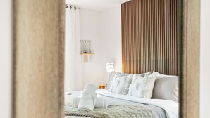 Ein Schlafzimmer mit einem Bett, einem Nachttisch, einer Lampe und einem an der Wand befestigten Regal.