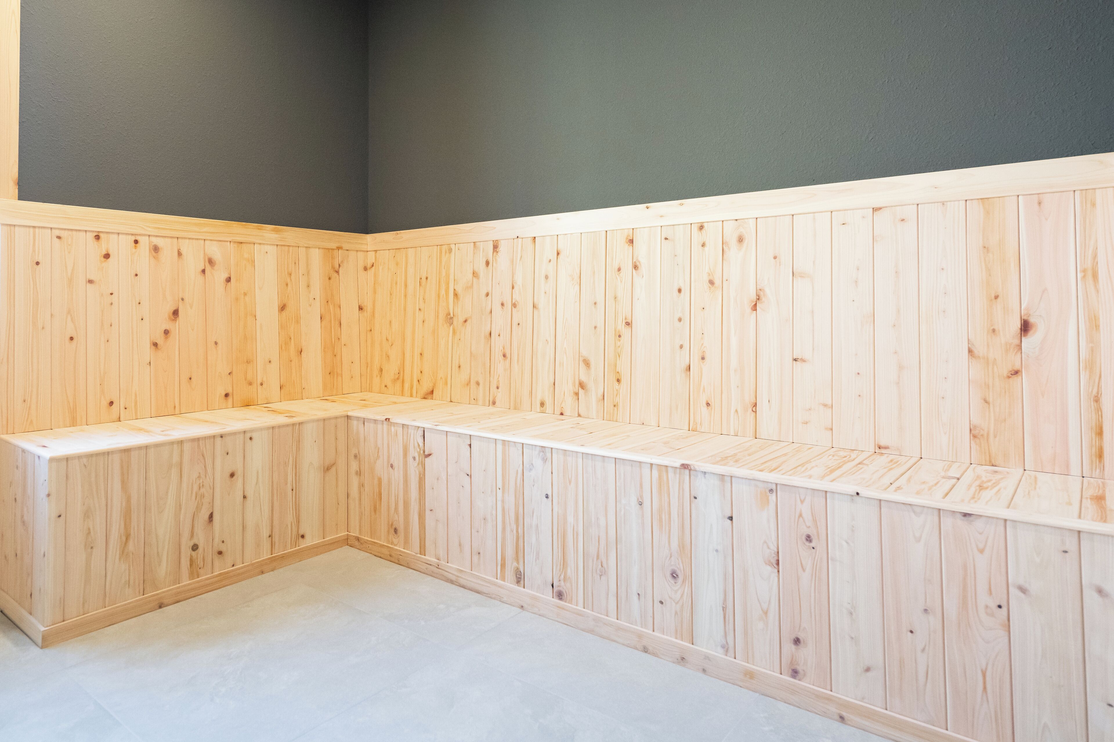 A corner room with wooden paneling and a bench.