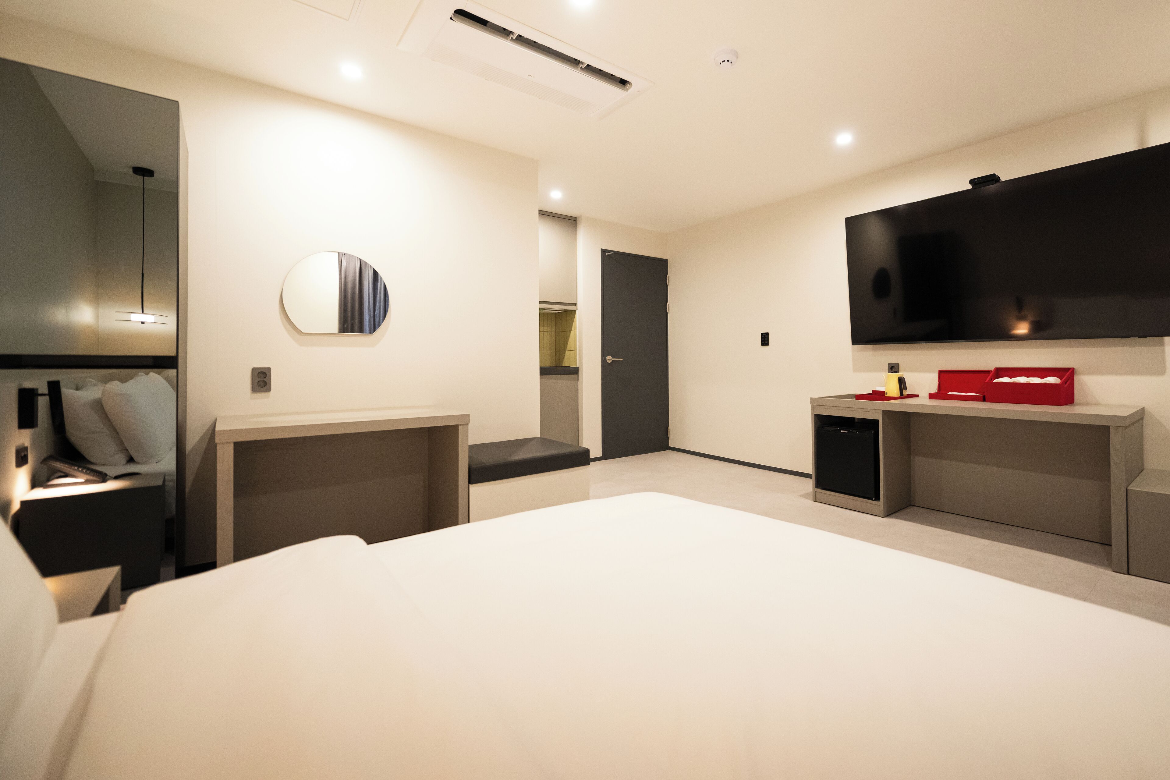Una habitación de hotel moderna con una cama grande, un televisor de pantalla plana, un escritorio pequeño y un espejo.