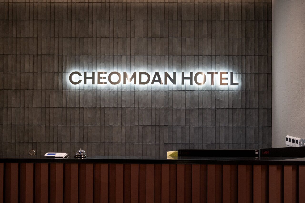 A reception desk with a sign that reads "CHEOMDAN HOTEL" in illuminated letters.