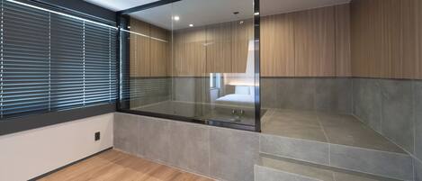 Un baño moderno con cabina de ducha de vidrio, piso de madera y pared con azulejos.