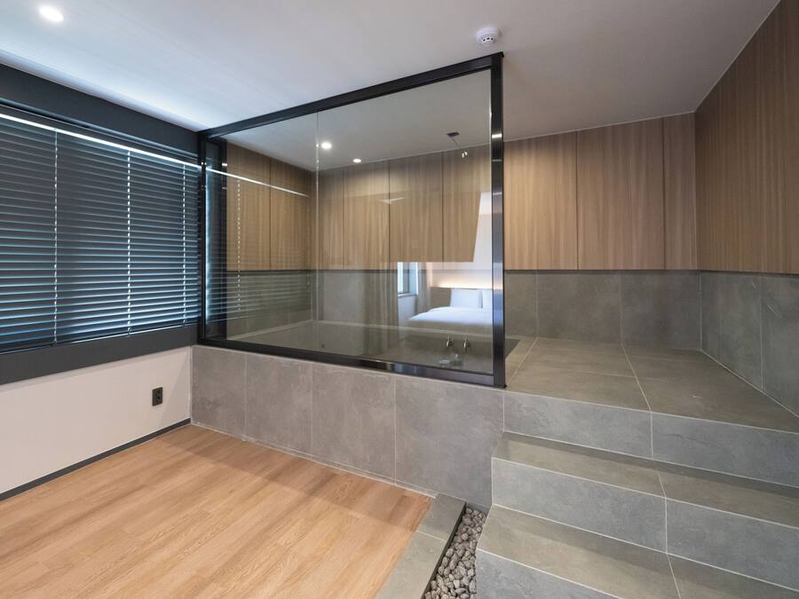 Un baño moderno con cabina de ducha de vidrio, piso de madera y pared con azulejos.