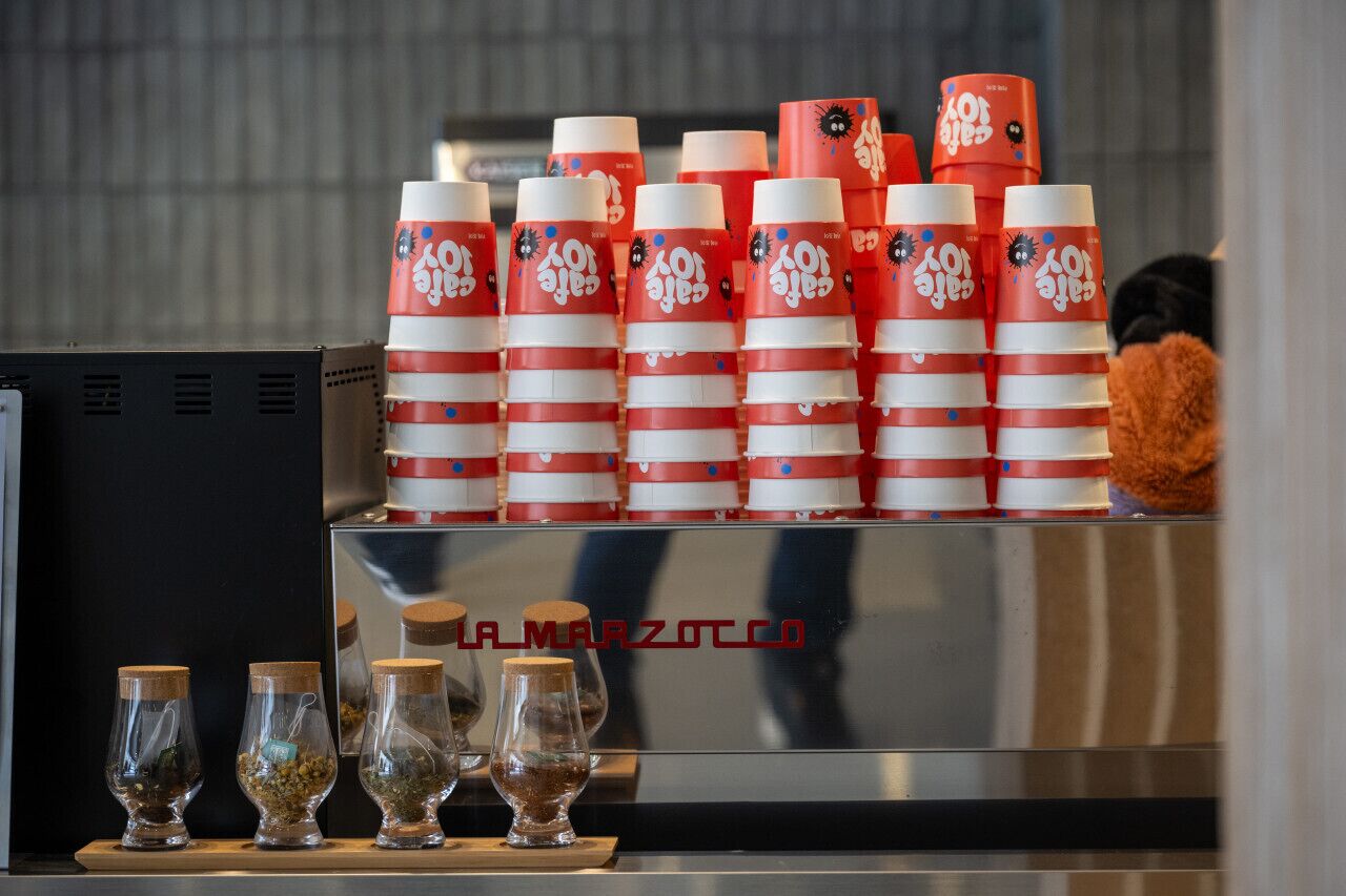 A coffee machine with a branded coffee cup display and a selection of coffee beans in small jars.