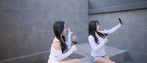 Dos personas sentadas en unos escalones, cada una sosteniendo una copa de vino.