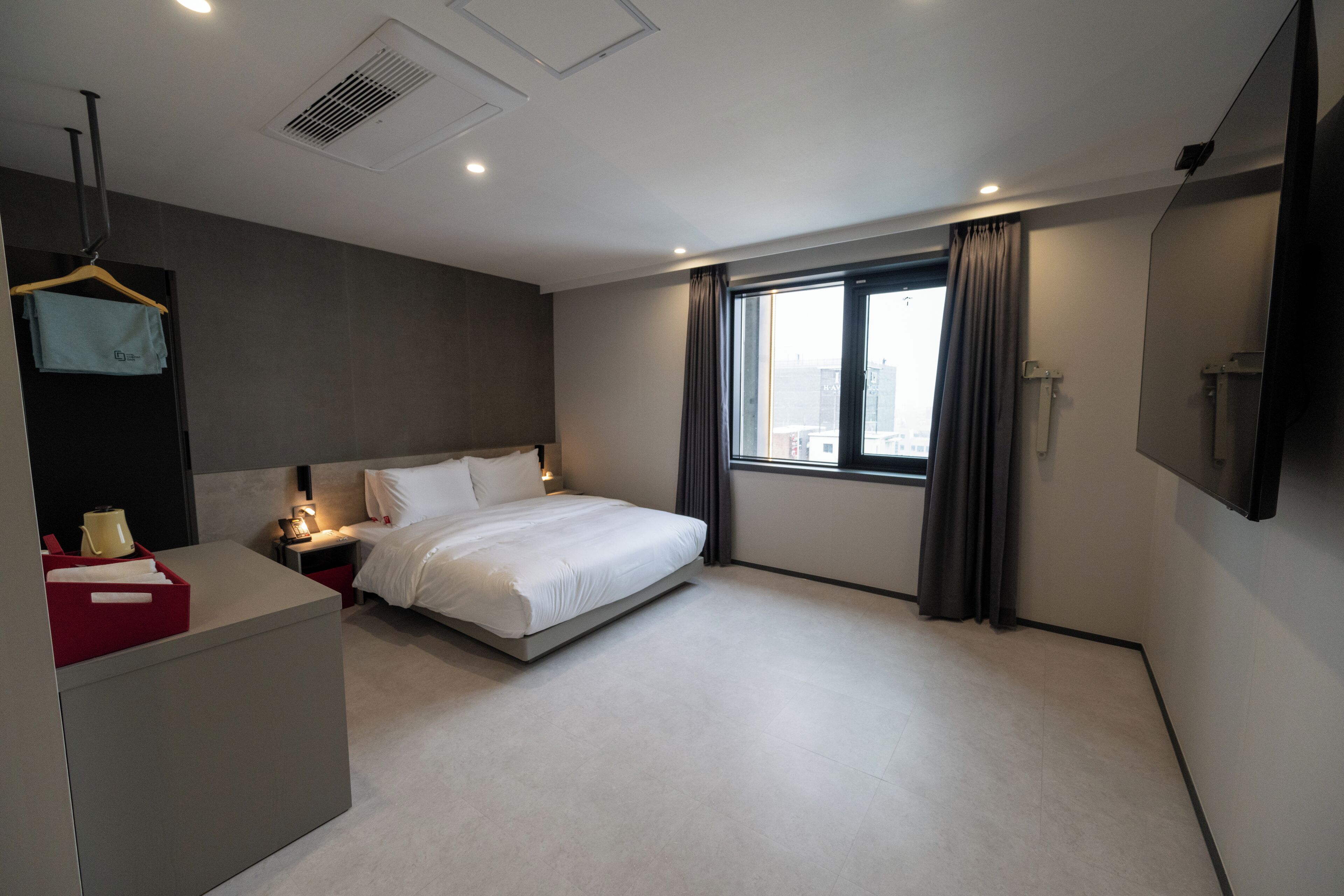 Una habitación de hotel moderna con una cama grande, mesitas de noche, un escritorio y un televisor.