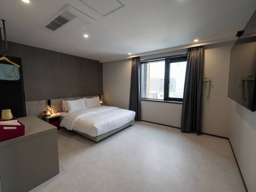 Una habitación de hotel moderna con una cama grande, mesitas de noche, un escritorio y un televisor.