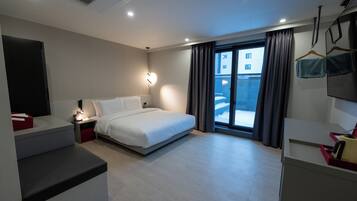 A modern hotel room with a bed, bedside table, and a view of the outside.