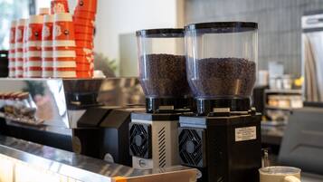 Une machine à café dotée de deux distributeurs de grains de café et d’un mousseur à lait, posée sur un comptoir.