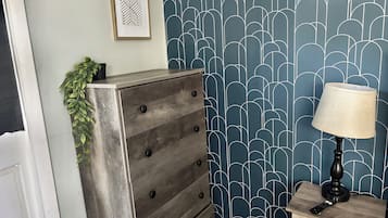 A room with a dresser, a lamp, and a wall with a geometric pattern.