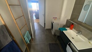 Un baño con lavamanos, espejo y perchero para toallas.