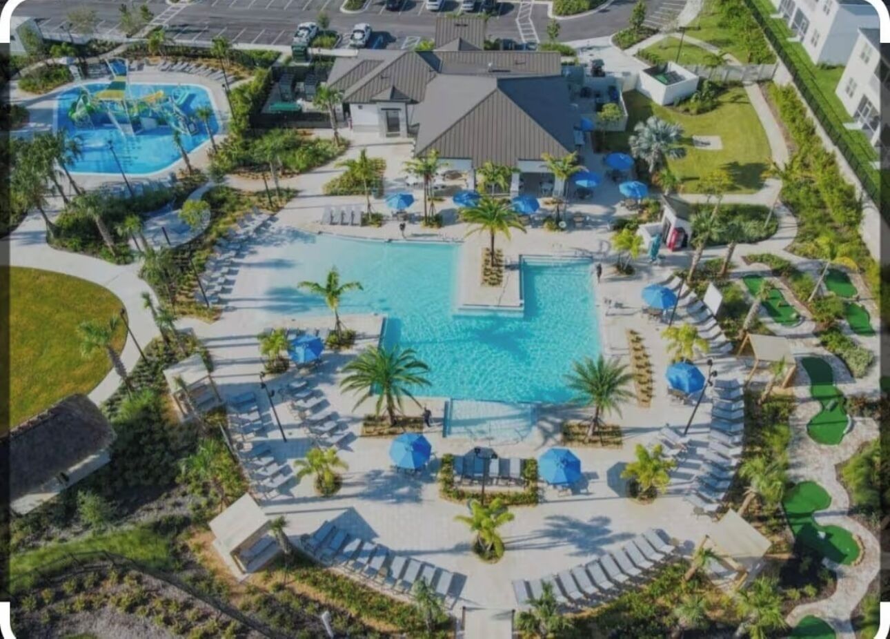 An aerial view of a resort with multiple swimming pools, sun loungers, and palm trees.